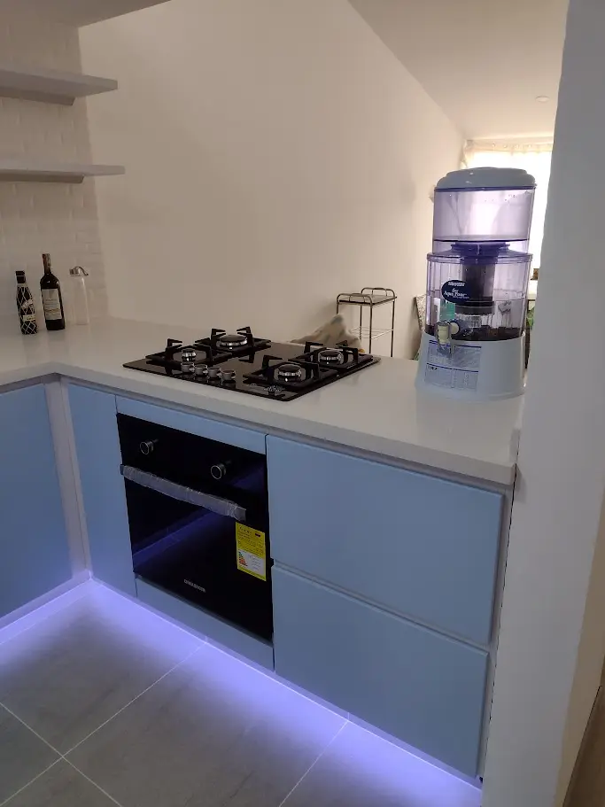 Detalle de gabinetes bajos azul pastel y mesón blanco en cocina integral moderna a medida en Bogotá