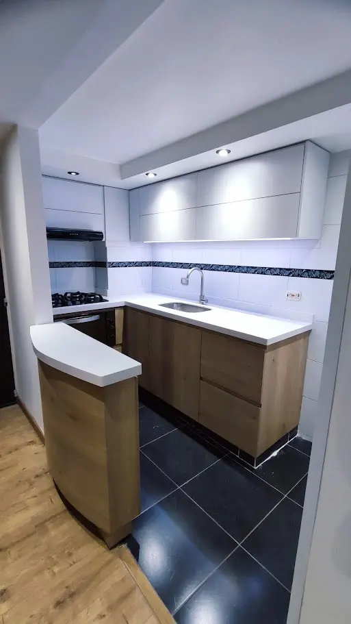 Diseño de cocina integral en Bogotá con barra curva, gabinetes bajos en madera y altos en blanco con iluminación LED
