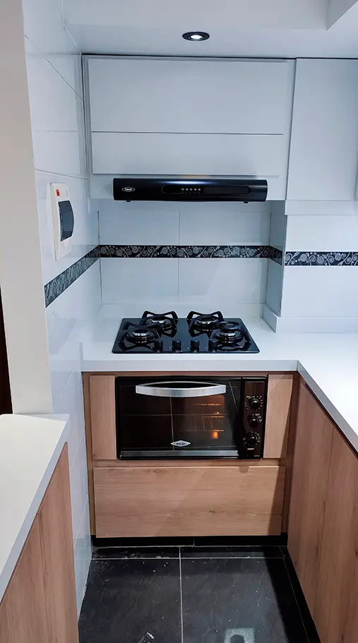 Diseño de cocina integral esquinera optimizando el espacio con muebles altos blancos y gabinetes bajos en madera clara