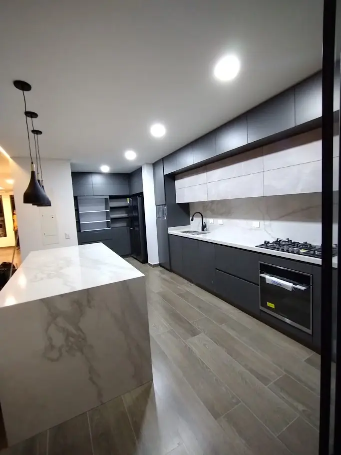 Espectacular cocina integral de lujo en Bogotá con isla en mármol estilo cascada y gabinetes modernos color carbón mate