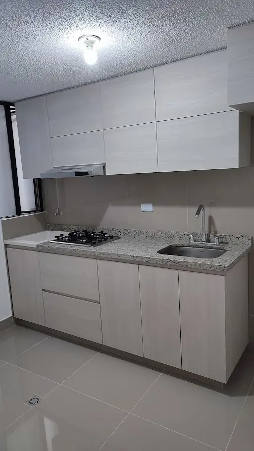 Cocina integral pequeña y moderna con gabinetes color beige minimalistas y mesón en granito claro