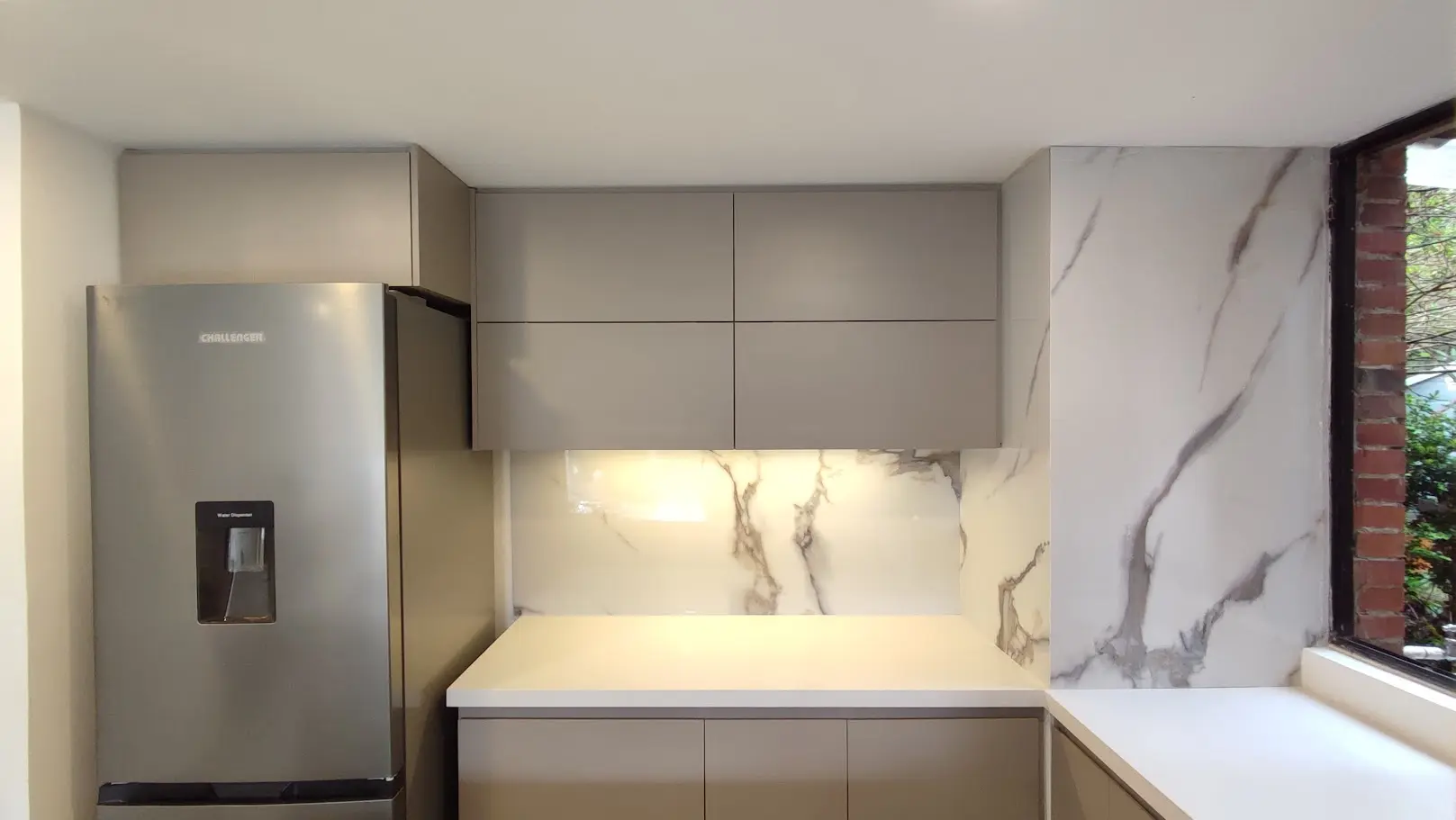 Detalle de gabinetes superiores color taupe mate y salpicadero en formato mármol blanco para cocina integral