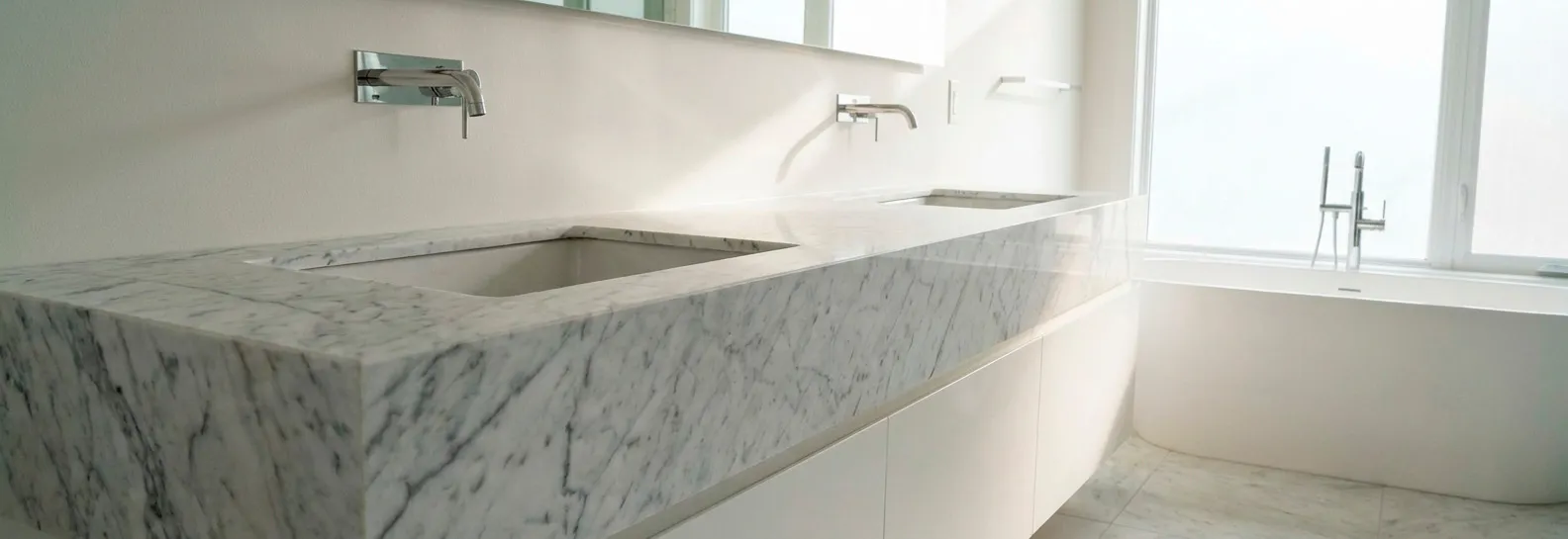 Lujoso mesón de mármol blanco con vetas grises en un baño moderno y luminoso, diseñado para brindar una experiencia de spa y exclusividad total.